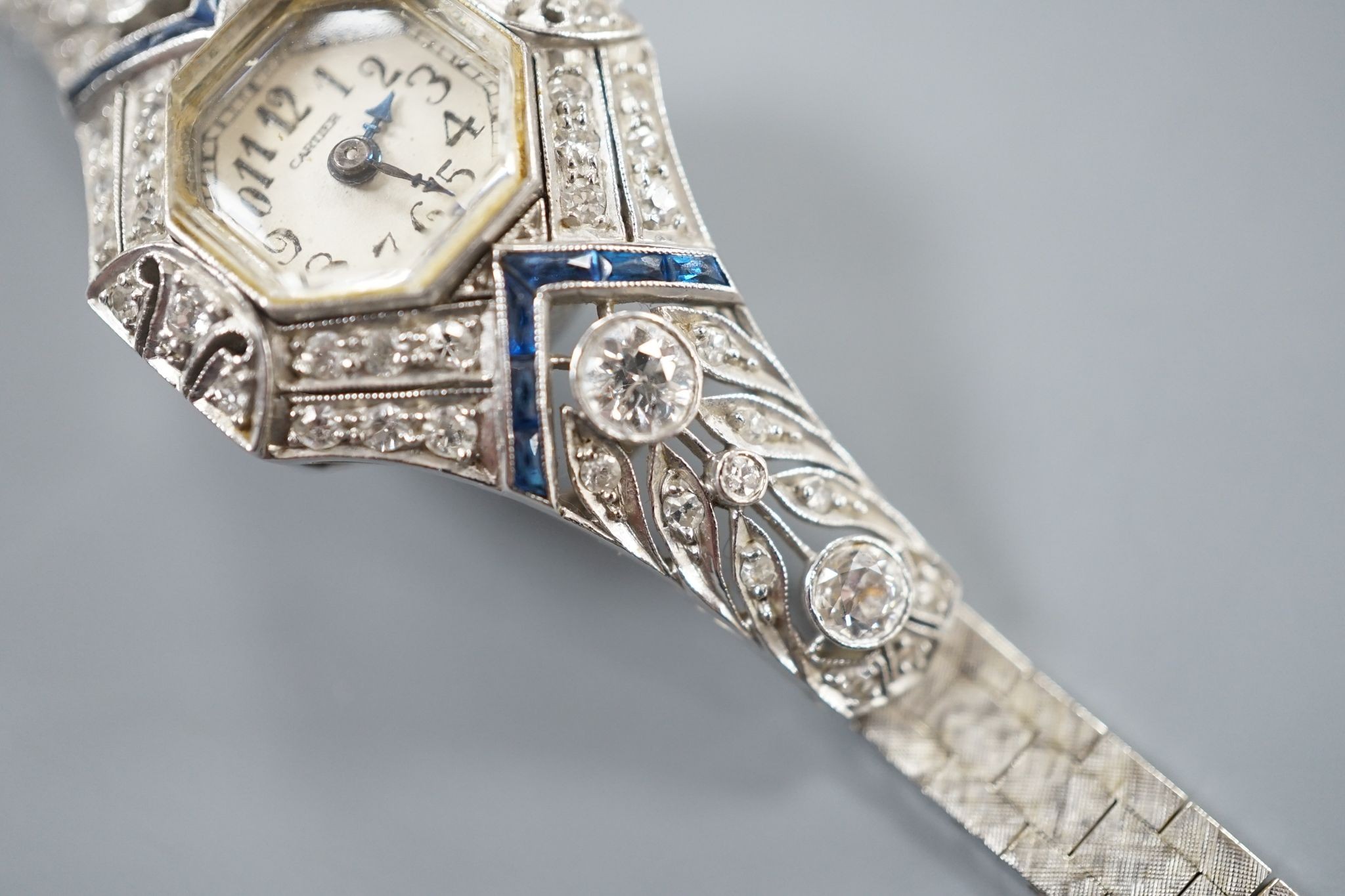A mid 20th century white metal, synthetic sapphire? and diamond set cocktail watch, with Bucherer manual wind movement and dial bearing the signature Cartier, on a 14k white metal bracelet, case diameter 22mm, gross weig